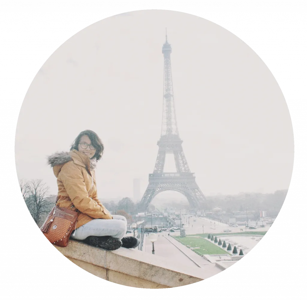 Fotografía de autora y dueña de la pagina web Laura Pérez, sentada sonriendo y al fondo la Torre Eiffel