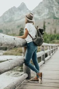 Mujer mirando un bosque mientras viaja por el mundo con su mascota
