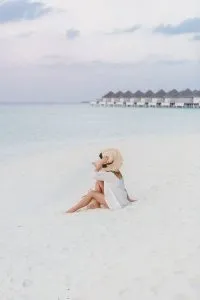 Mujer en la playa mientras viaja por el mundo cuidando mascotas