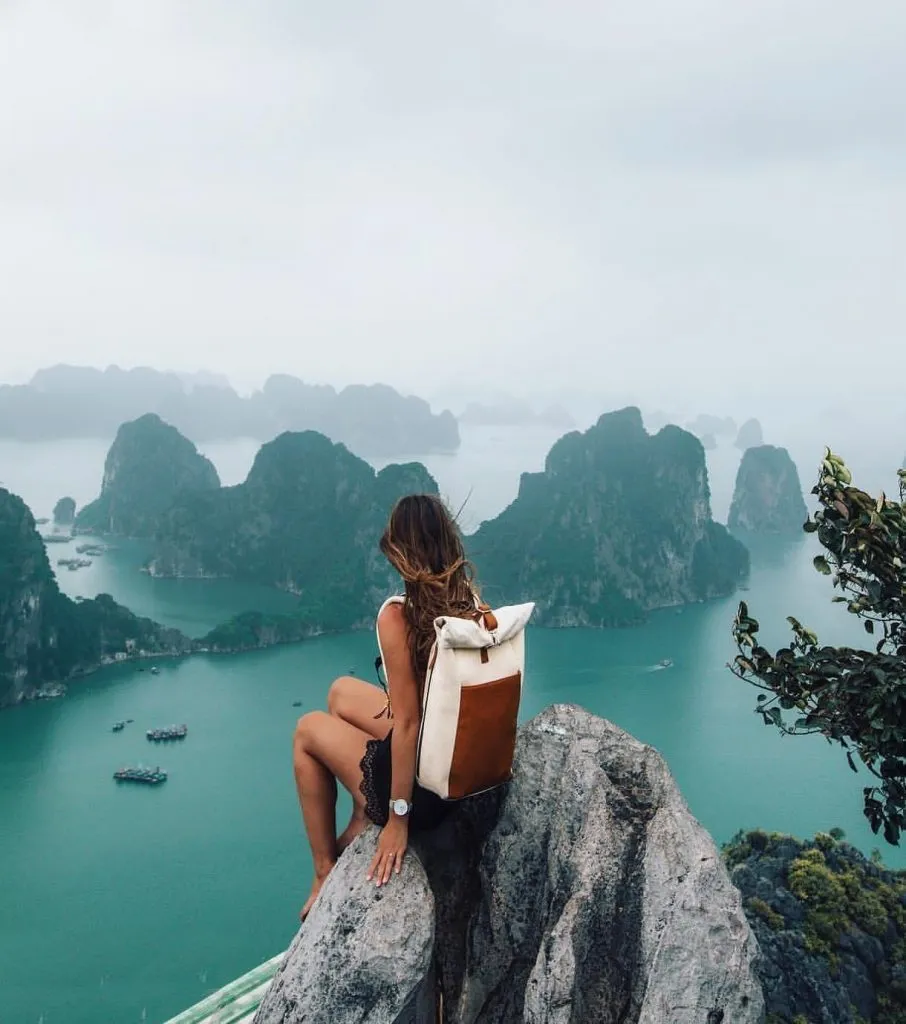 Mujer sentada frente a una montañas, mientras gana dinero y viaja por el mundo 