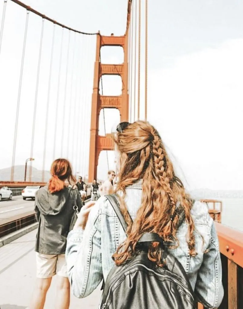 Mujeres caminando de espaldas, al fondo el puente de Brrokling