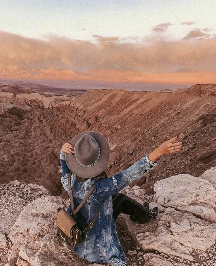 Mujer sentada en frente de montañas en una ruta de roadtrip por la costa oeste